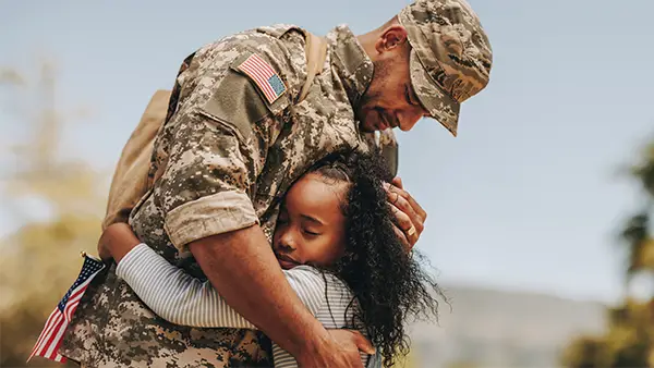 Military dad hugging daughter